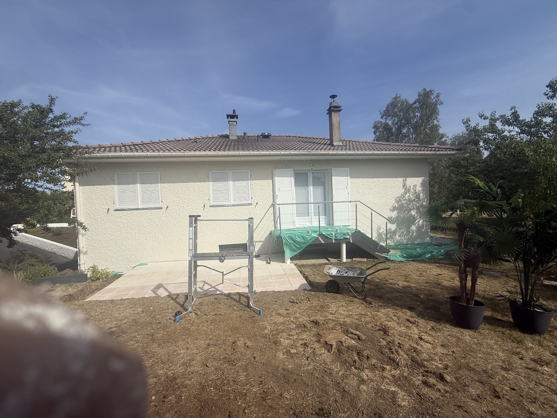 Maison dont la façade vient d'être repeinte, marches protégées par une bâche