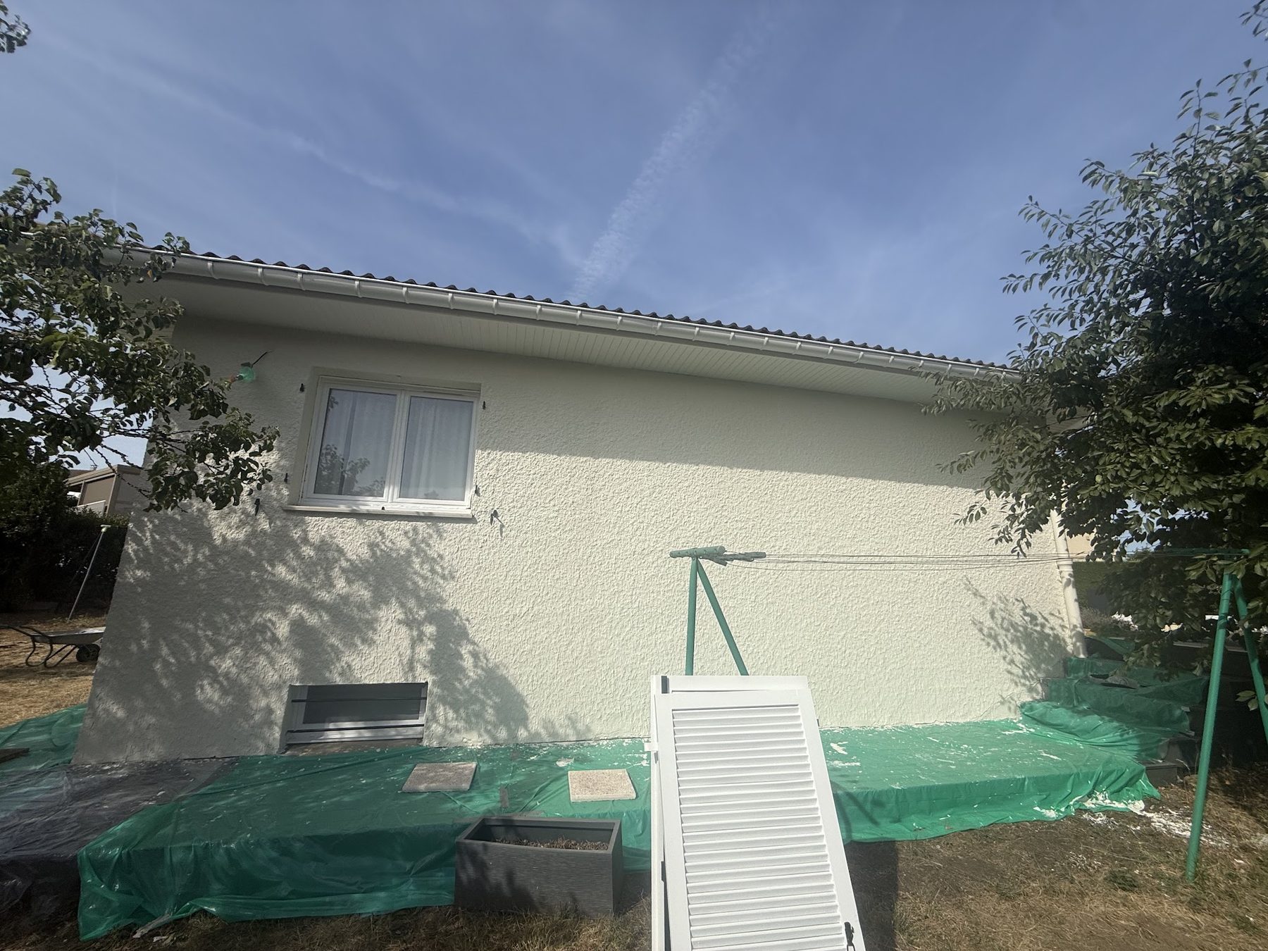 Façade en cours de mise en peinture, sol protégé